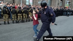 Полицейский задерживает подростка на митинге против пенсионной реформы в Санкт-Петербурге, 9 сентября 2018