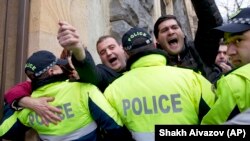 Police try to prevent demonstrators from blocking entrances to parliament and prevent lawmakers from entering the building in Tbilisi on December 12.