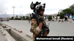 An Afghan security forces member stands guard at the site of the May 30 blast in Kabul.