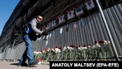 Sankt-Peterburg, COVID-19-dan ölen saglyk işgärleriniň hatyrasyna gül goýýan adam. 1-nji maý, 2020.  