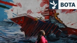 Një grua iraniane ec pranë një murali në një rrugë në Teheran.