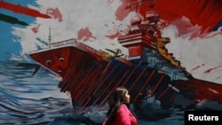 Iranka prolazi pored murala na ulici u Teheranu.