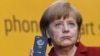 Angela Merkel arătându-și telefonul mobil (“Handy”) în octombrie 2013, când s-a dovedit că serviciile secrete din SUA au putut monitoriza telefoanul cancelarei germane. Despre denumirea germană de “Handy” pentru un telefon mobil — mai multe aici, în revista presei.