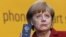 Angela Merkel arătându-și telefonul mobil (“Handy”) în octombrie 2013, când s-a dovedit că serviciile secrete din SUA au putut monitoriza telefoanul cancelarei germane. Despre denumirea germană de “Handy” pentru un telefon mobil — mai multe aici, în revista presei.