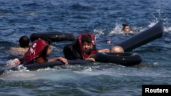 Refugees float as they hold a tube after a dinghy carrying Syrian and Afghan refugees deflated some 100m away before reaching the Greek island of Lesbos, September 2015.