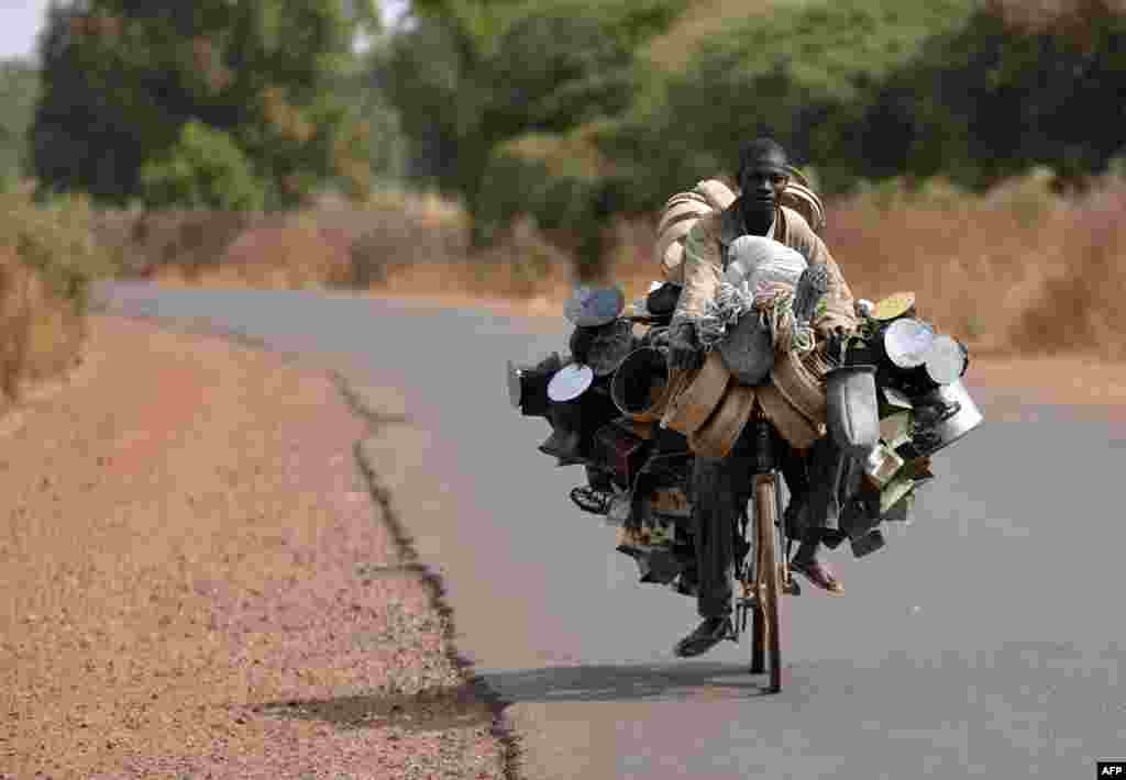 A man carries good to sell as he rides a bicyle en route to a market near Segou, north of Bamako, Mali. (AFP/Eric Feferberg)