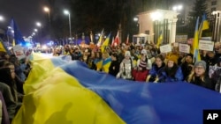 Participants carry a giant Ukrainian flag to mark the one-year anniversary of the Russian invasion of Ukraine in front of the Russian Embassy in Warsaw on February 24. 