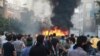 Supporters of Iran's presidential candidate Mir Hossein Mousavi standing by a burning vehicle during protests in Tehran, 19Jun2009