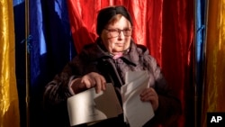 A woman exits a voting booth in Bucharest on November 24. As of 3 p.m., Romanian election officials said turnout was 32 percent, up from 29.2 percent at the same time in the 2019 vote.