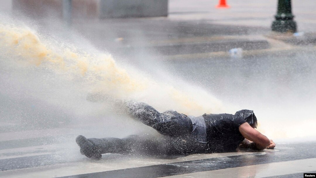 Струя водомета сбивает с ног демонстранта в Анкаре. 16 июня 2013 г.