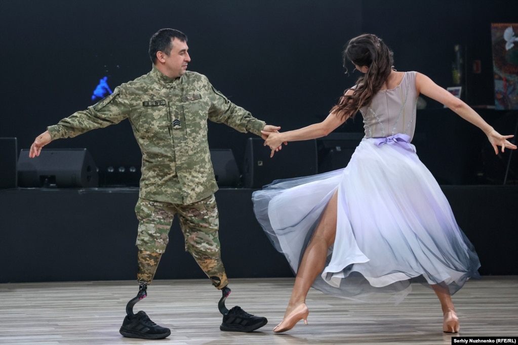 آرتم، سرباز اوکراینی، روز ۳۱ مه در مراسم خیریه «قلبهای شجاع» در کییف، همراه با شریک خود پولینا میرقصد. این نظامی، در توصیف رقصیدن بهعنوان فردی با قطع هر دو پا گفت: «از یک طرف خیلی ساده است، اما از طرف دیگر از نظر جسمی بسیار دشوار است. باید رویا داشت، هدف تعیین کرد، به جلو حرکت کرد و با عمل نشان داد که هیچچیز غیرممکن نیست.»عکس: سرهی نوجننکو / بخش اوکراینی رادیو اروپای آزاد/رادیو آزادی