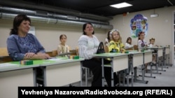 Інна Маслова (зліва) зі своїми учнями та їхніми батьками в укритті, обладнаному під класи