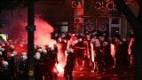 A flare burns as Serbian Riot Police move towards protesters as tens of thousands gather in central Belgrade to issue an "ultimatum" to the populist government to call early elections after months of student-led strikes across the country, in Belgrade, on
