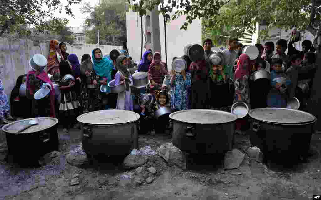 Afghan children hold dishes as they wait to receive food donated by a private charity during the holy month of Ramadan in Jalalabad on June 30. (AFP/Noorullah Shirzada)