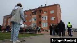 People gather outside a damaged residential building following a Ukrainian drone strike in the Ramensky district of the Moscow region.