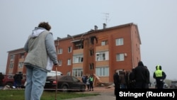 Ljudi ispred oštećene stambene zgrade nakon napada ukrajinskim dronom u okrugu Ramenski u Moskovskoj oblasti.