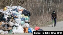 An elderly man wearing a respirator rides a bicycle past garbage bags to the grocery store during a lockdown, in Ramenskoye, outside Moscow, on April 9.