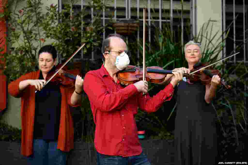 Members of Opera Australia Orchestra perform outside the offices of Opera Australia to call on the company to reconsider its decision to stand down musicians without pay following a coronavirus outbreak in Sydney.