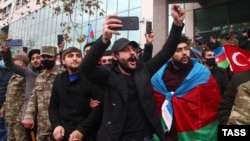 People cheer during a military parade in Baku on December 10.