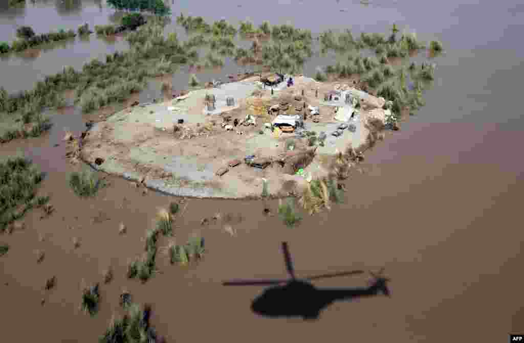 The shadow of a Pakistani Army helicopter is seen next to land surrounded by floodwaters where affected villagers gathered to seek higher ground in the Rajanpur district, in Punjab Province, on August 6. (AFP/SS Mirza)