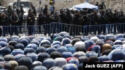 Israeli riot police keep watch as Palestinian Muslim worshippers pray outside Jerusalem's old city on July 28, 2017.