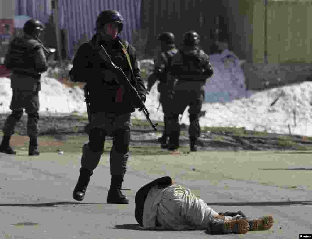 A wounded protester lies on the ground as Afghan policemen keep watch during a protest in Kabul on February 23.