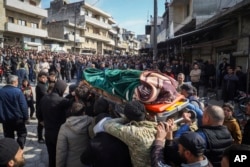 Rude și vecini participă la procesiunea funerară a patru membri ai forțelor de securitate siriene uciși în confruntările cu loialiștii președintelui demis, Bashar al-Assad, în nord-vestul Siriei, pe 8 martie.