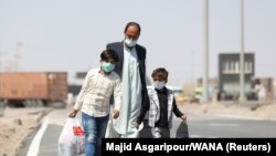Un tată și cei doi copii ai săi trec granița Afganistanului.
