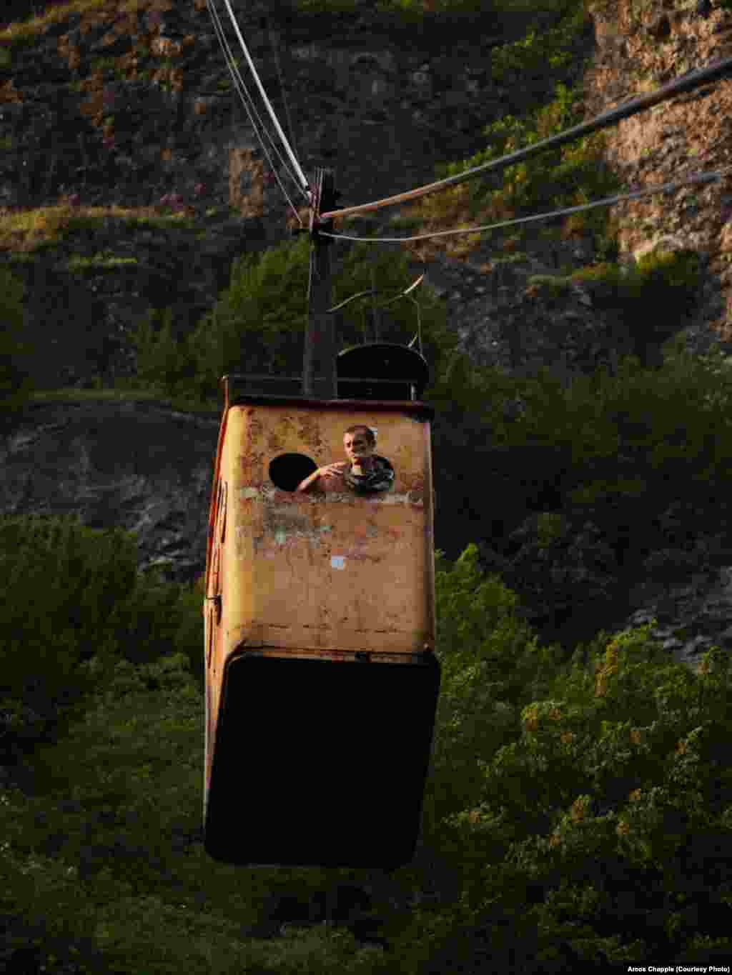 A miner smokes a cigarette through the window of the &quot;Peace&quot; tramway which runs from the center of town up to the entrance of one of the manganese mines. The cable cars are owned by the mining company, but are open to the public.