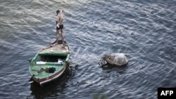Чоловік-єгиптянин миється на човні, річка Ніл, Каїр, 22 червня 2015 року
