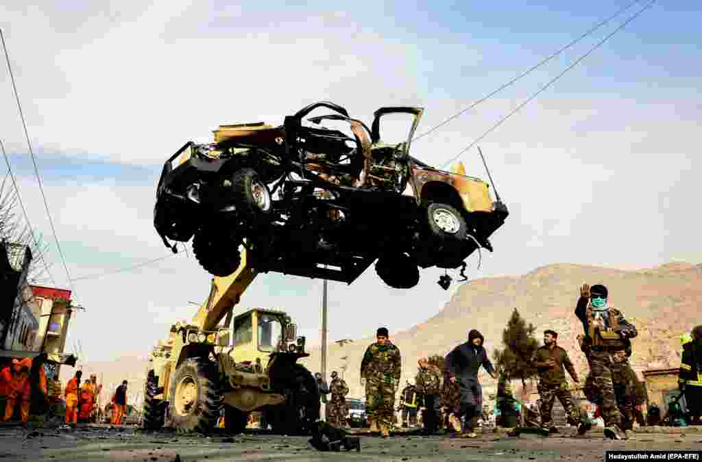 Afghan police officers remove the wreckage of a damaged car in the aftermath of a bomb explosion in Kabul on February 1. (epa-EFE/Hedayatullah Amid)