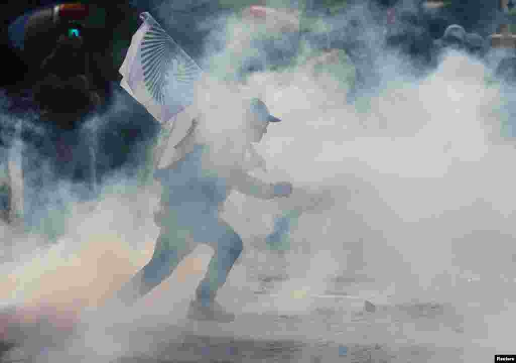 Un bărbat aleargă cu un steag al fermierilor prin fum.