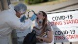 A Kazakh health worker takes a swab from a woman at a mobile testing station for COVID-19 in Almaty earlier this week. 