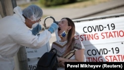 A Kazakh health worker takes a swab from a woman at a mobile testing station for COVID-19 in Almaty earlier this week. 