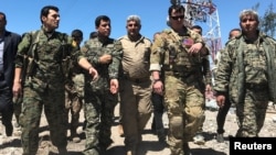A U.S. military commander (2nd right) walks with Kurdish fighters from the People's Protection Units (YPG) at the YPG headquarters that was hit by Turkish air strikes in Mount Karachok near Malikiya, Syria, on April 25.