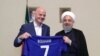 A handout picture released by the office of Iranian President Hassan Rouhani shows him (R) and FIFA President Gianni Infantino holding a jersey with Rouhani's name during Infantino's visit to the capital Tehran on March 1, 2018.