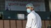 KAZAKHSTAN -- A vendor wearing a protective face mask waits for customers near an information banner placed outside the coronavirus disease (COVID-19) vaccination center at a food market in Almaty, April 14, 2021