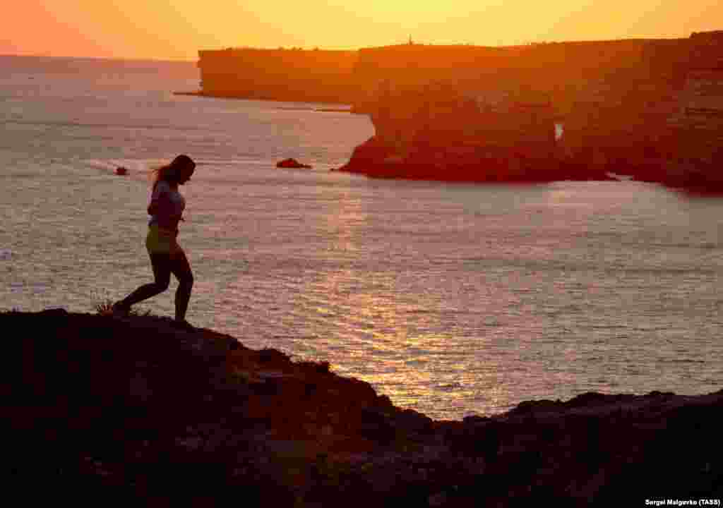 A woman jogs by the sea near the Atlesh fishing site in Crimea, Ukraine. (TASS/Sergei Malgavko)