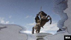Споменикот Воин на коњ се гледа во вирче на плоштадот Македонија во Скопје после дожд