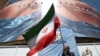 Čovek drži iransku zastavu ispred anti-američkog bilborda u Teheranu, 31. maj 2026. 