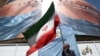 A man in Tehran holds an Iranian flag near an anti-US billboard depicting  US President Donald Trump and the Strait of Hormuz. 
