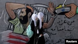 Djevojke prolaze pored murala koji prikazuje palestinskog zatvorenika štrajkača glađu Maher Al-Akhrasa