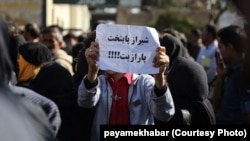 People gathered in front of the governorate of Fars, on January 09, 2017, in protest against satellite jamming emissions in Shiraz. One of the protesters holds a sign that reads "Shiraz, the capital of parasite".