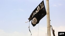 Боец коалиции SDF снимает флаг боевиков-исламистов
