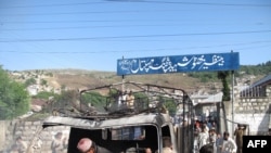 Pakistani gather around the wreckage of a police truck torched by demonstrators in Abbottabad on April 12.