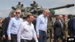 26 iunie, Pabrade, Lituania: Secretarul general al NATO, Jens Stoltenberg (s) se alătură președintelui Lituaniei, Gitanas Nauseda (d) și ministrului apărării din germania, Boris Pistorius (c) la un exercițiu militar germano-lituanian.