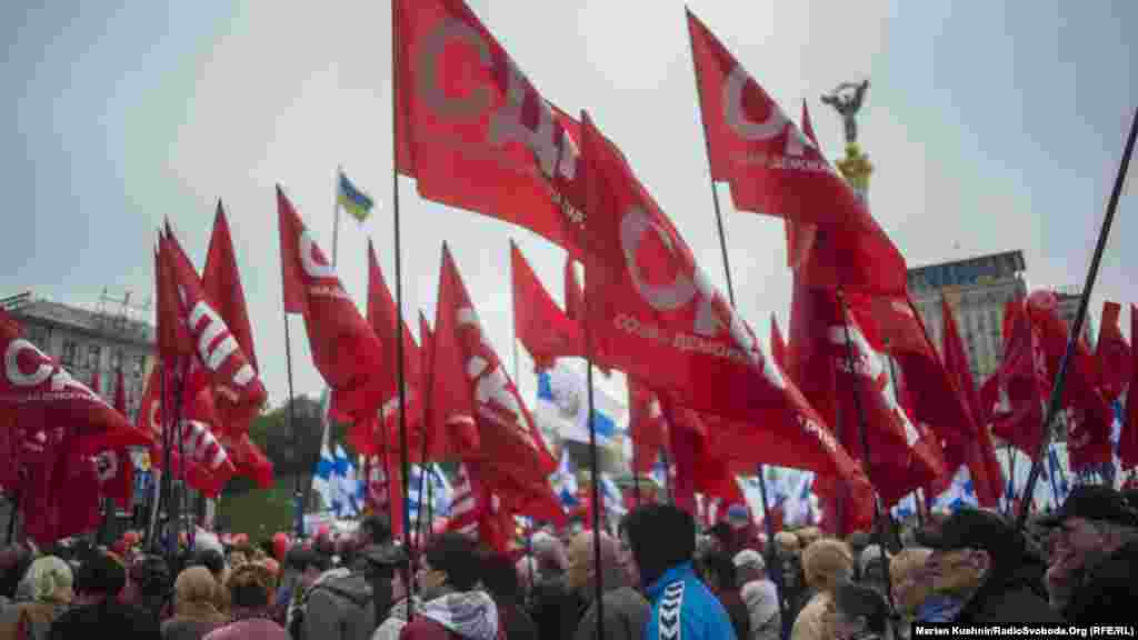 Колона із декількох сотень людей із червоними прапорами проходить повз майдан Незалежності