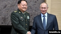 Ресей президенті Владимир Путин (оң жақта) елге сапармен келген қытай генералы Чжан Юсямен қол алысып тұр. 2017 жыл.