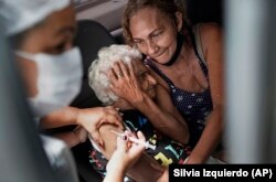 Женщина получает вакцину CoronaVac в рамках приоритетной программы вакцинации пожилых людей от COVID-19 в центре вакцинации для автомобилистов в Рио-де-Жанейро. 1 февраля 2021 года.