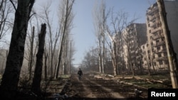 Un locuitor lângă blocuri avariate de un atac militar rus în orașul Kostiantinivka, din regiunea Donețk. Potrivit unui plan de pace american în 28 de puncte, regiunea ar urma să fie cedată Rusiei.